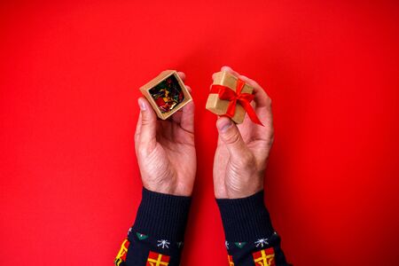 Male hands on a red background opens a Christmas presentの写真素材