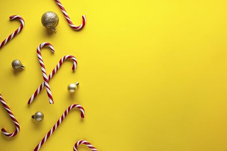 Christmas concept. Christmas candies with golden toys on a yellow background.の写真素材