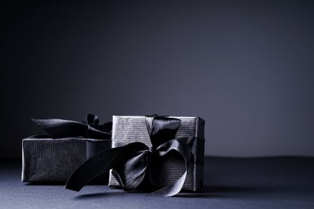 Black Friday. Gifts in black packaging with black ribbons on a black and gray background.の写真素材