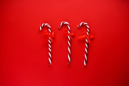 Christmas concept. Christmas candy cane with red ribbon on a red background. Flat lay.の写真素材