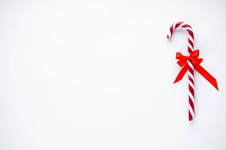 Christmas concept. Christmas candy with a red bow on a white background. Place for text. Flat lay.の写真素材