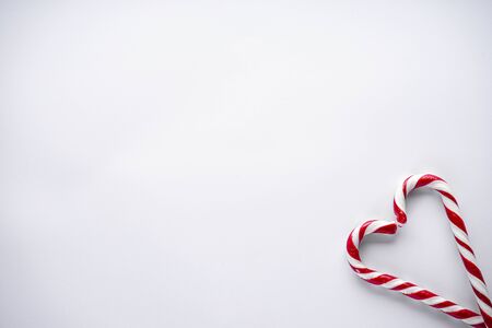 Christmas concept. Christmas candy in the corner in the form of a heart on a white background. Place for text, flat lay.の写真素材