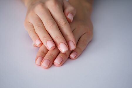 Female hands with a nice manicure on gray background, nude.の写真素材
