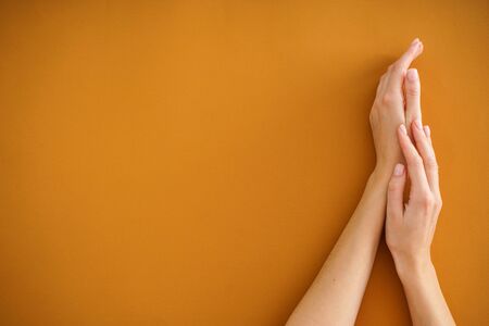 Hands of a young woman with beautiful manicure on a beige background. Female manicure. Flat lay, place for text.の写真素材