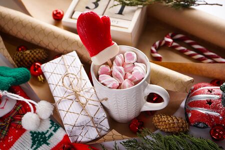 Christmas, New Year holiday background. Greeting card, sparkling toys, a mug of hot chocolate, marshmallows, a red car, an old wooden calendar, Christmas sweets, a gift, a Christmas sock, cones, a Christmas tree branch.の写真素材