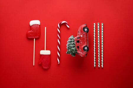 Christmas composition with a red car with a green Christmas tree on a red background. Flat lay. Christmas concept.の写真素材