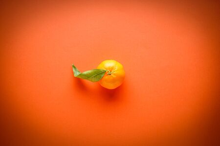 Fresh orange mandarin with green leaves, on an orange background, flat lay.の写真素材