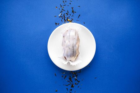 Flat lay. Eclair in a white plate on a blue background with confetti.の写真素材
