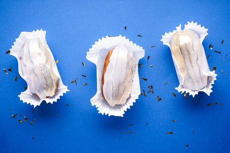 French dessert. Three eclairs on a blue flat background, flat lay, closeup.の写真素材