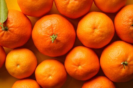 Close-up orange tangerines on a yellow background.