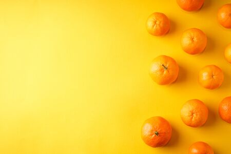 Orange mandarines on a yellow background with place for text.の写真素材
