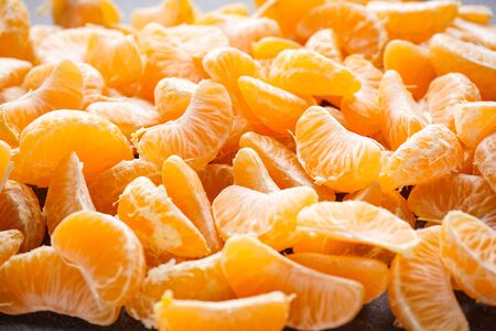 Slices of ripe mandarin on a dark background.の写真素材