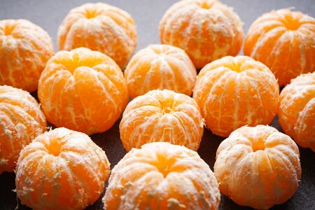 Peeled ripe tangerine on a dark background close-up.の写真素材
