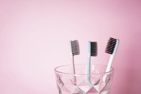 Toothbrushes in a glass on a pink background with space for text. Dental and healthcare concept.の写真素材