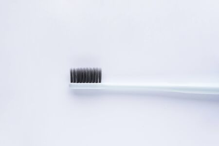 Blue toothbrush with black bristles on a white background. Closeup.