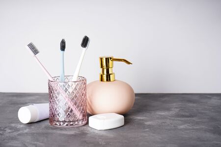 Toothbrushes in a glass, dental floss, toothpaste and soap dispenser on a gray background.の写真素材