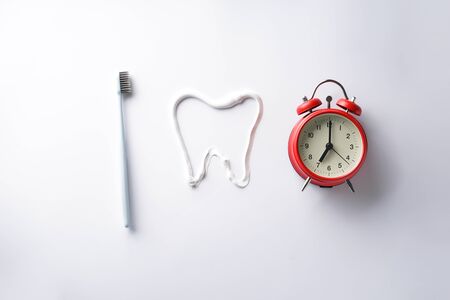 Teeth brushing concept. Toothbrush and alarm clock on a white background.の写真素材