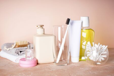 Toothbrush in a glass and other toiletries on a beige background