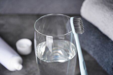 Toothbrush, glass of water and towels on a gray background. Close-up. Dental and healthcare concept.の写真素材