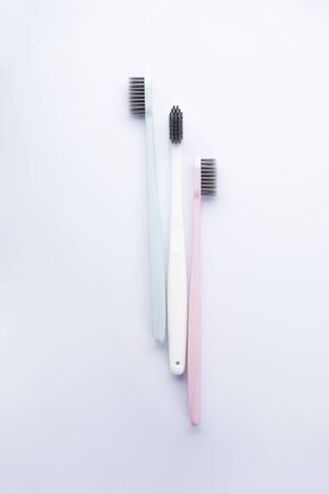 Multi-colored toothbrushes with black bristles on a white background, flat lay. Isolated.