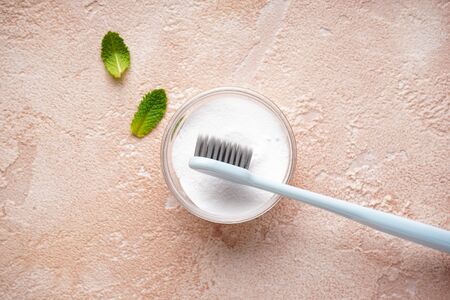 Toothbrush and tooth powder on a beige background with mint leaves, flat lay.の写真素材