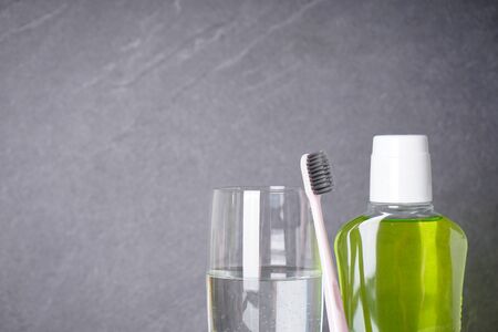 Toothbrush, mouthwash and glass of water on a gray background close-up with a place for text. Dental and morning concept.の写真素材