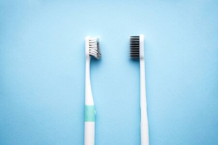 Dental and healthcare concept. New and old toothbrushes on a blue background, close-up, flat lay.