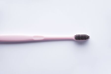 Pink toothbrush with black bristles on a white background. Flat lay の写真素材