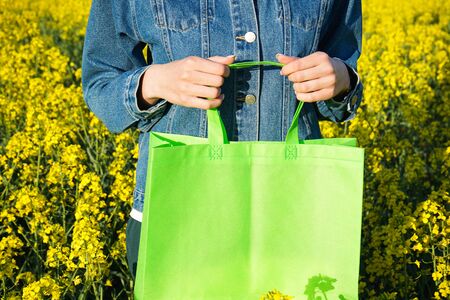 Eco bag. Woman holding an eco bag outdoors with space for text. Mockup for design.