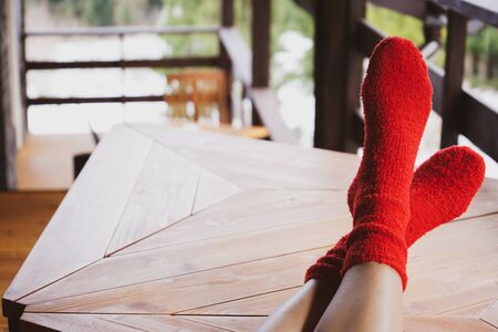 Legs of a young woman in socks on a wooden table on a terrace with a view of the forest. Outside, with space far text.の写真素材