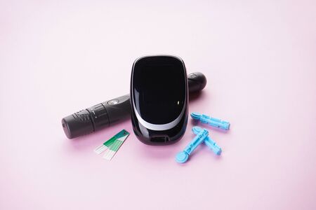 Digital glucometer and lancet pen on a pink background. Close-up. Diabetes concept, medical technology.の写真素材