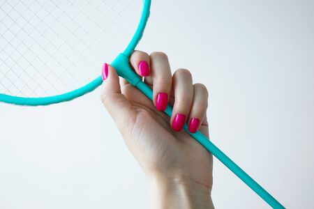 Beauty and sport concept. Beautiful female hand holds a badminton racket on a white background. Beautiful manicure.の写真素材