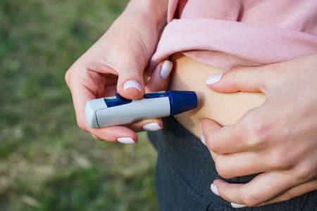 Lancet pen in the hand of a young woman doing the test, close-up.の写真素材