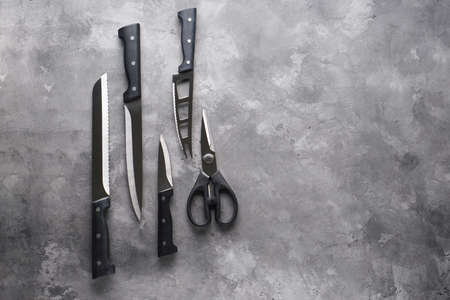 A set of knives. Various kitchen utensils on a gray table background, flat lay, with place for text.の写真素材