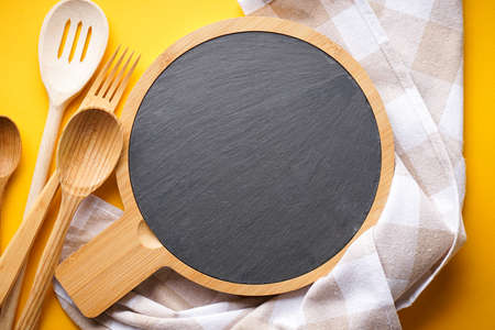 Kitchen utensils with a towel on a yellow background with space for text, top view. Close-up.