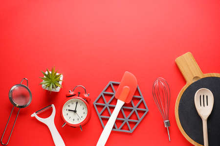 Various kitchen utensils on a red background with space for text, flat lay.の写真素材