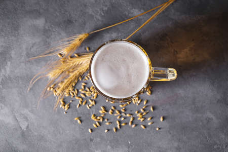 Glass of light beer and barley on a gray background, top view.