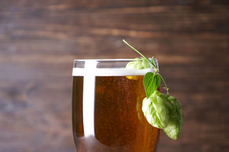 Glass of light beer on a wooden background, close-up.