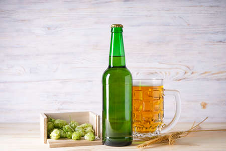 Light beer and hop cones on a wood background.
