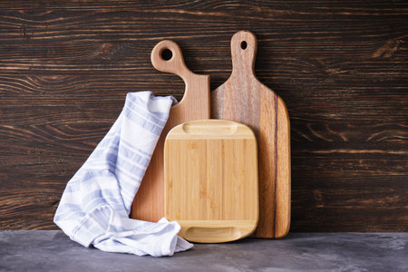 Wooden cutting boards and kitchen towel on wooden background