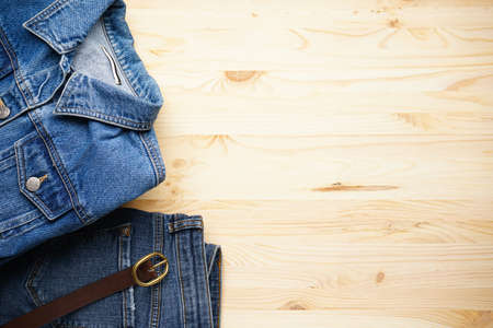 Jeans women's jacket and denim pants on the wooden background, top view. Space for text.の写真素材