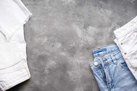 Jeans women's and denim pants over gray background, flat lay. Place for text.の写真素材