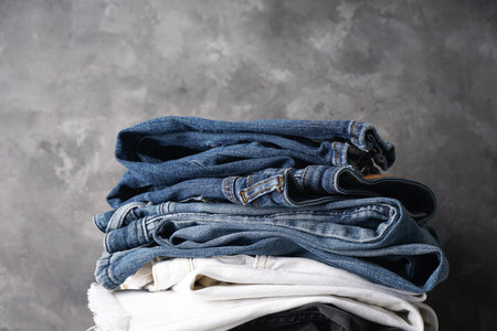 Jeans of different colors. Folded jeans on gray background,