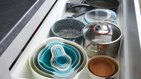 Open drawer with different utensils and cutlery in kitchen.