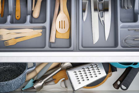 Open drawer with different utensils and cutlery in kitchen, flat lay.の写真素材