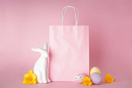 Happy Easter concept. Easter bunny and colored Easter eggs with paper bag on pink background, place for textの写真素材