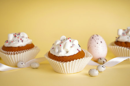 Easter cupcakes and easter eggs, funny easter treats on yellow background, close-up.