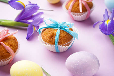 Easter treats, colorful cupcakes and flowers Irises on a pink background, close-up.の写真素材