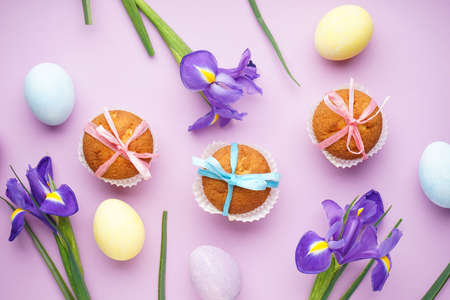 Easter treats, colorful cupcakes and flowers Irises on a pink background, top view.の写真素材