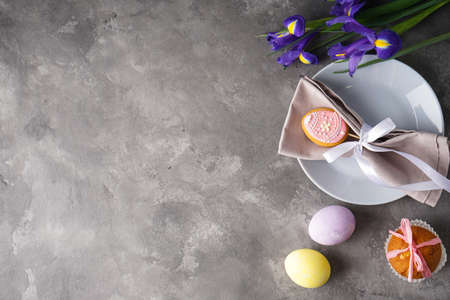 Easter holiday table setting and plates with colorful eggs on a gray background. Easter holiday...